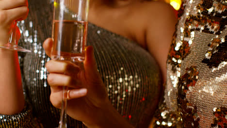 Close-Up-Of-Two-Women-In-Nightclub-Or-Bar-Celebrating-Drinking-Alcohol-With-Sparkling-Lights
